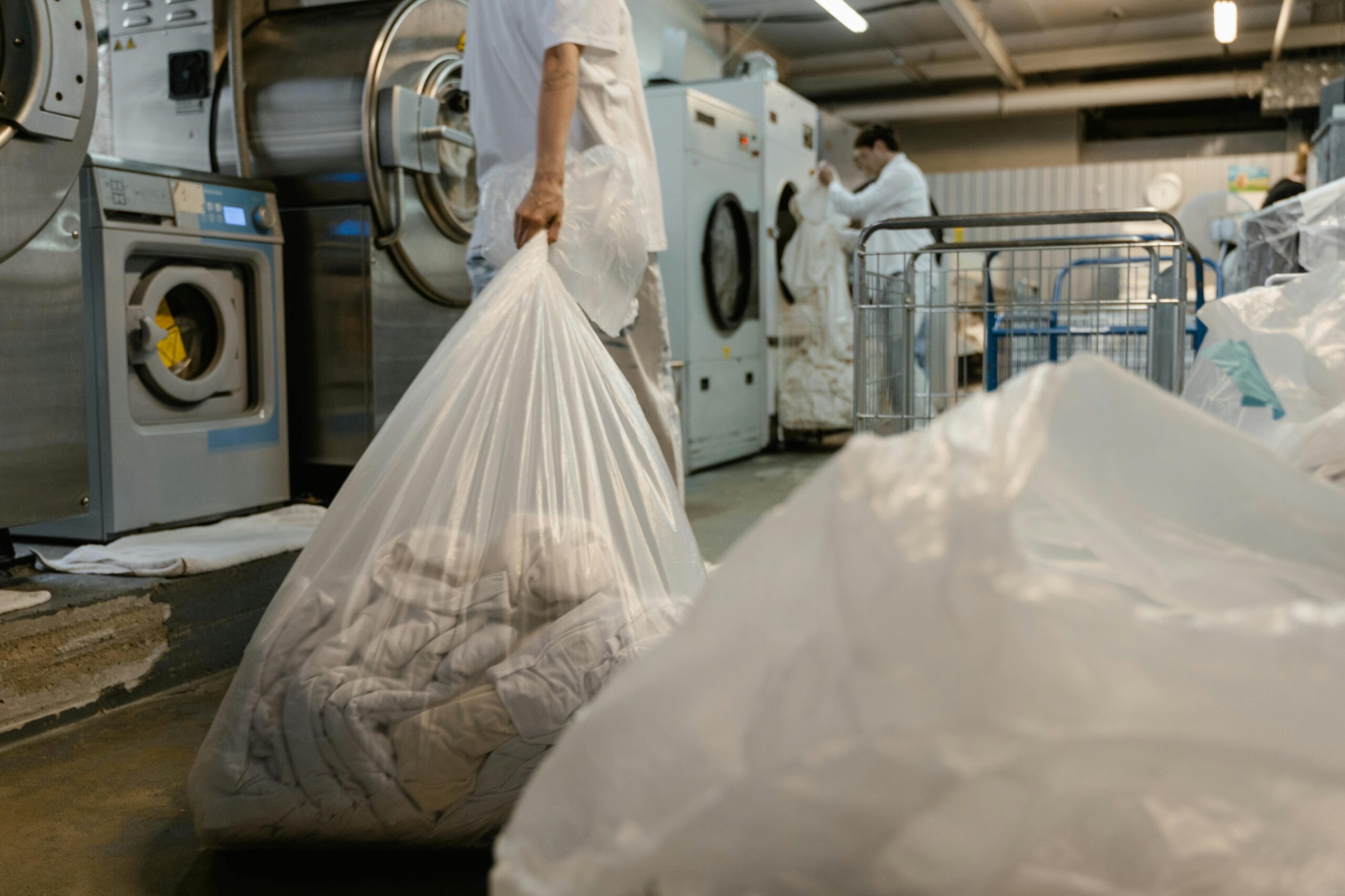 Person carrying laundry bag in a commercial laundry facility.